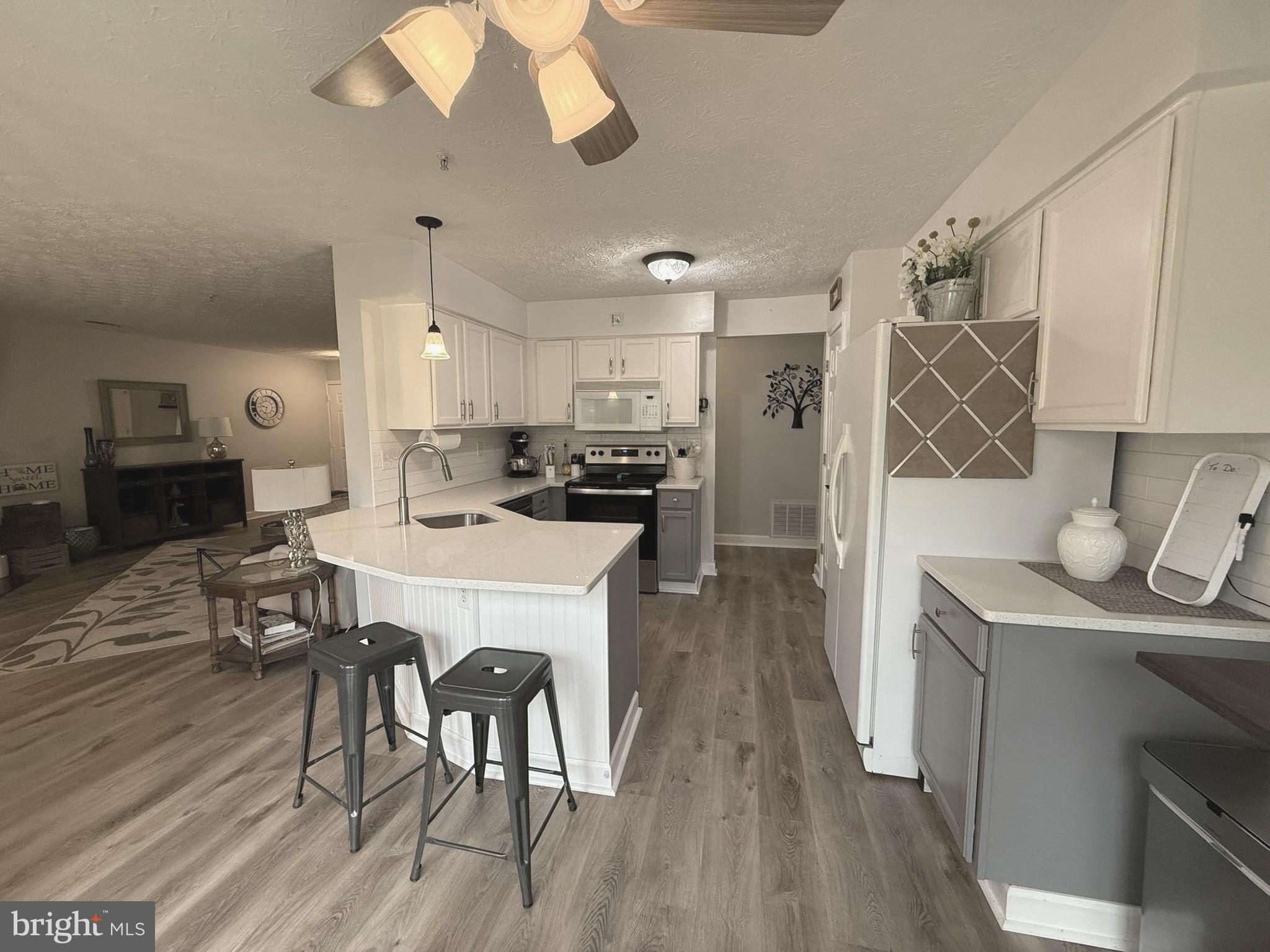 6343 Springwater Terrace, Unit 1012 Frederick, MD 21701 - Photo 11 of 39 a kitchen with kitchen island stainless steel appliances a dining table chairs sink and cabinets