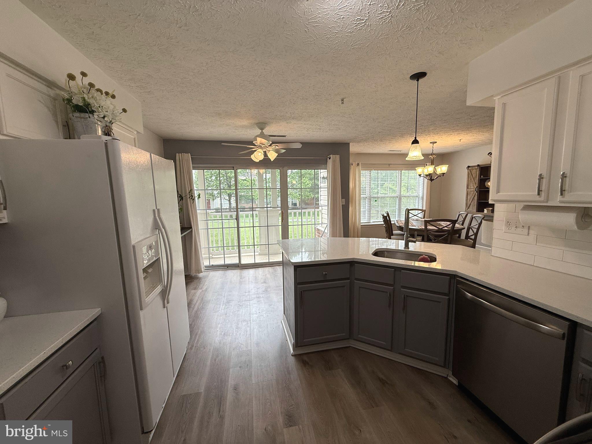 6343 Springwater Terrace, Unit 1012 Frederick, MD 21701 - Photo 20 of 39 a open kitchen with stainless steel appliances granite countertop a refrigerator a sink dishwasher a stove and white countertops with wooden floor