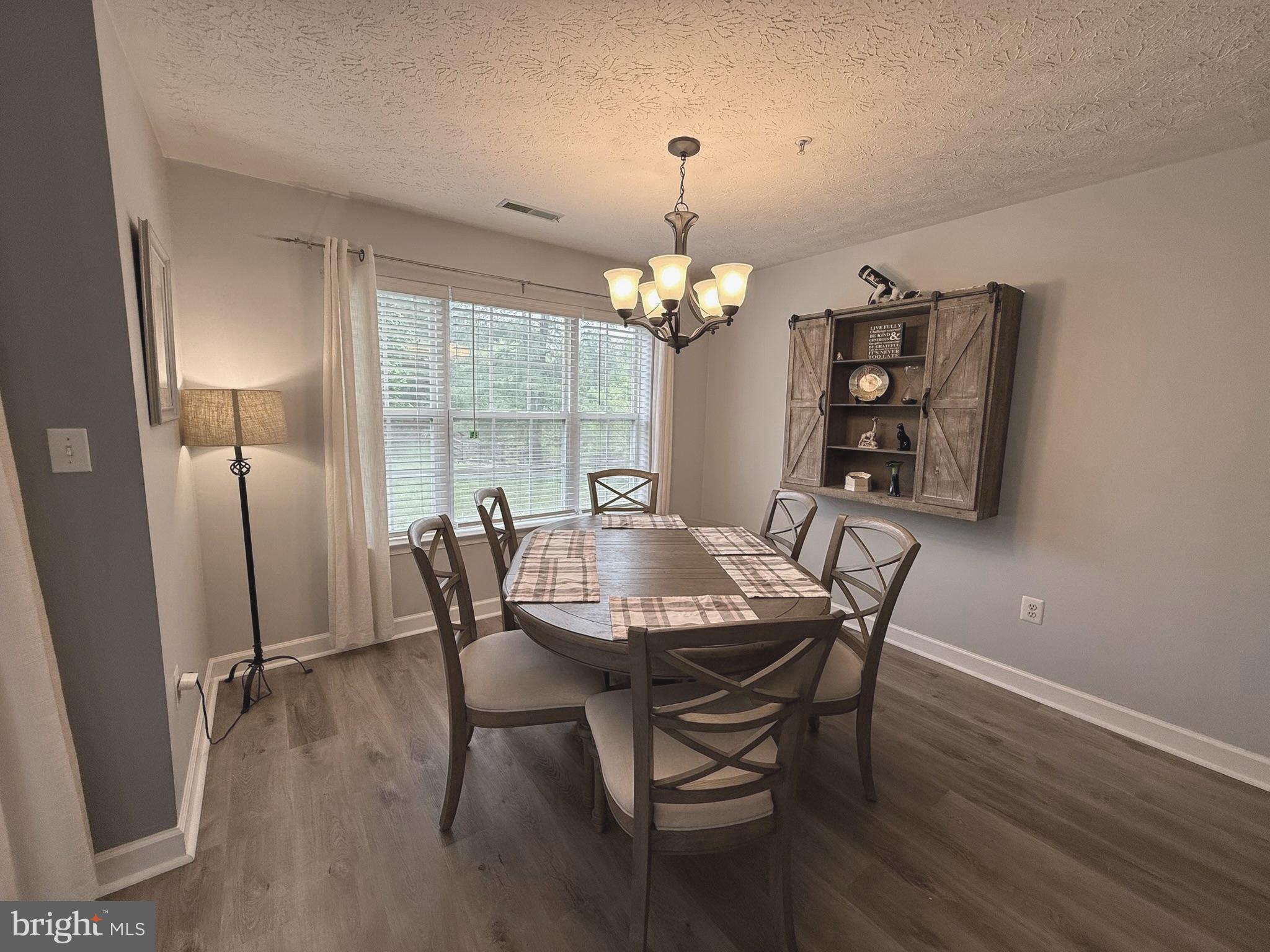 6343 Springwater Terrace, Unit 1012 Frederick, MD 21701 - Photo 8 of 39 a dining room with furniture a chandelier and wooden floor