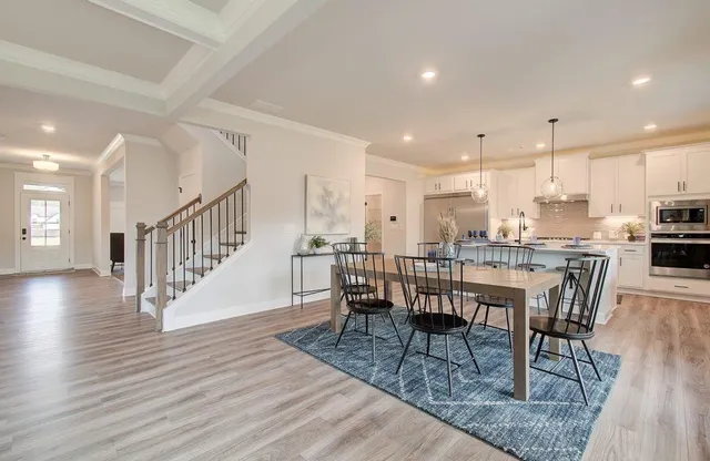 an open kitchen with dining table chairs wooden floor and a kitchen view