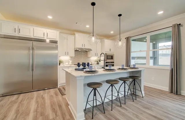 a kitchen with kitchen island a stove a refrigerator a sink dishwasher with a dining table and chairs