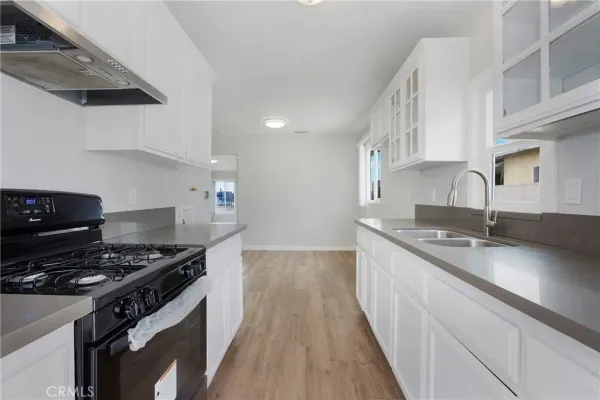 a kitchen with granite countertop a sink stove and cabinets
