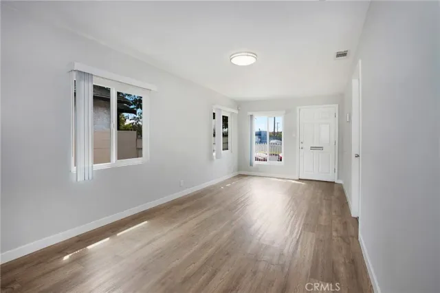 a view of an empty room with window and wooden floor