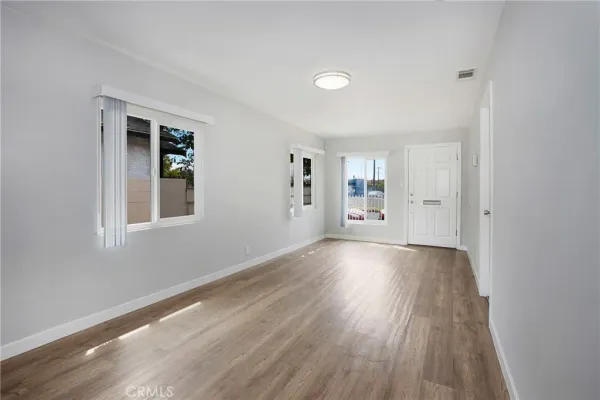 a view of an empty room with window and wooden floor