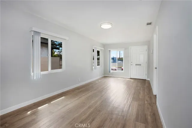 a view of an empty room with window and wooden floor