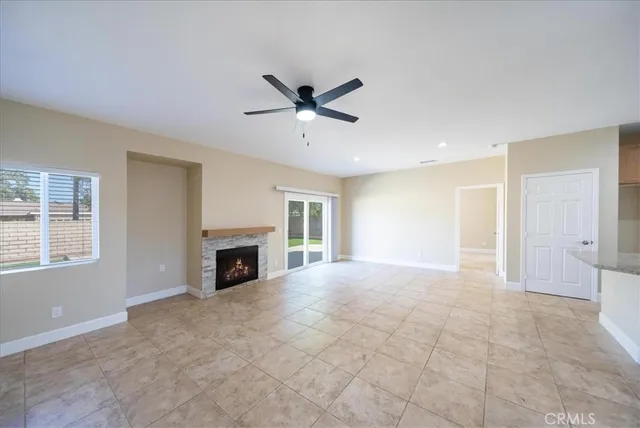 a view of a livingroom with a fireplace a ceiling fan and windows in a room