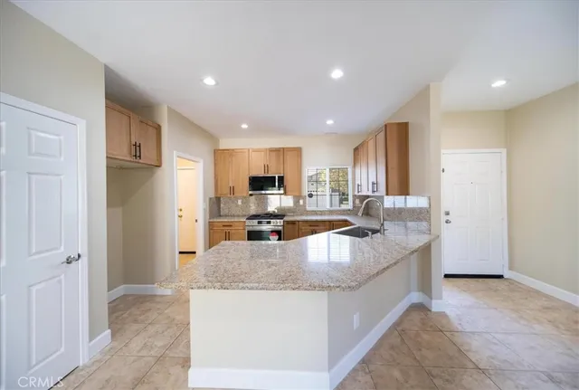 a kitchen with stainless steel appliances granite countertop a refrigerator a sink and a stove