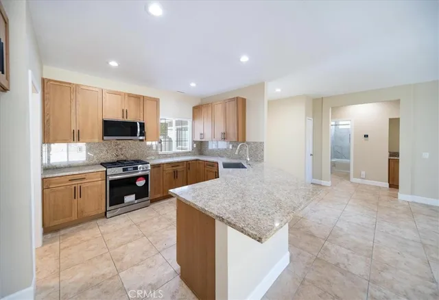 a kitchen with stainless steel appliances granite countertop a stove top oven a sink a counter top space cabinets and a window