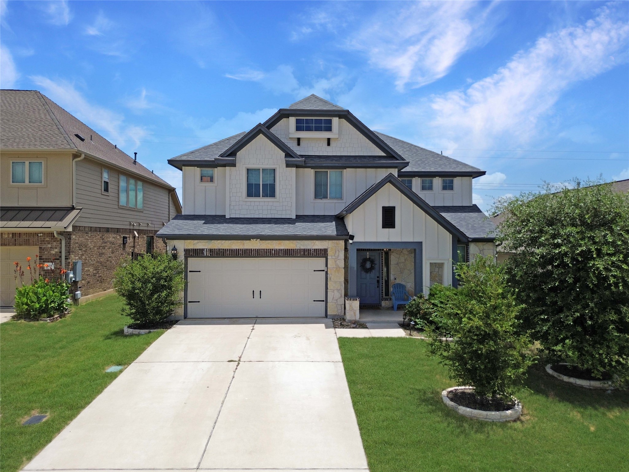Discover a charming two-story residence with a paved driveway and well-maintained green landscaping.