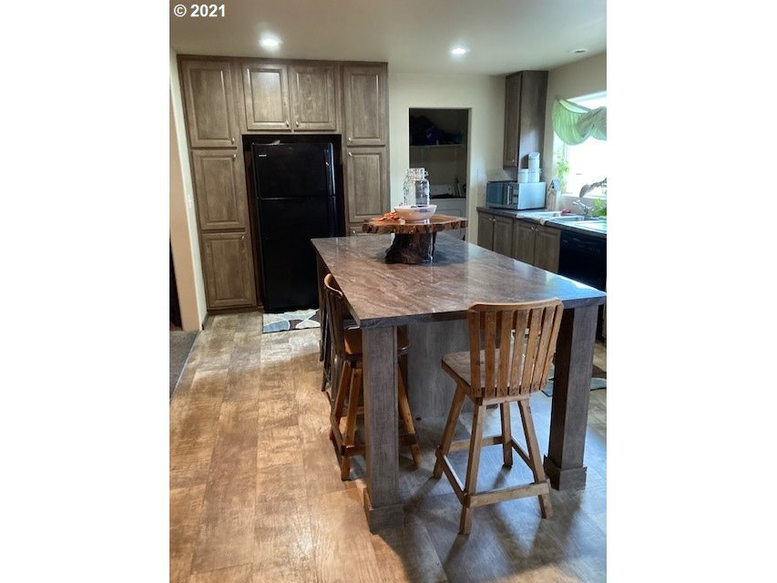 356 Southeast 3rd Street Pendleton, OR 97801 - Photo 5 of 20 a kitchen with stainless steel appliances kitchen island granite countertop a refrigerator a stove a microwave oven with white cabinets and wooden floor