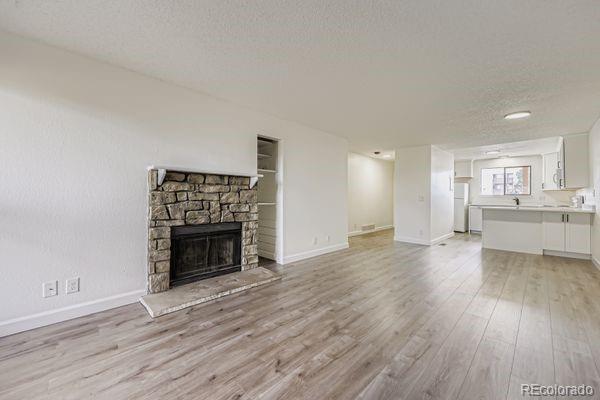 8678 Decatur Street, Unit 275 Westminster, CO 80031 - Photo 4 of 26 a view of an empty room and a kitchen with wooden floor and a fireplace