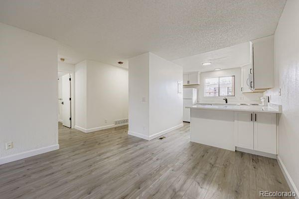 8678 Decatur Street, Unit 275 Westminster, CO 80031 - Photo 7 of 26 a kitchen with wooden floors and white cabinets