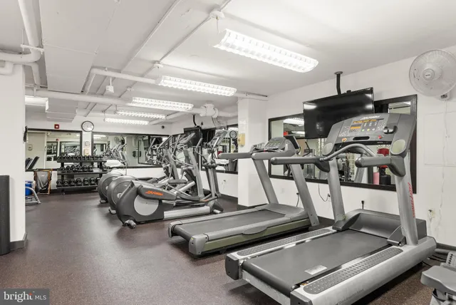 a view of a patio with a dining table and chairs under an umbrella with barbeque grill and wooden floor