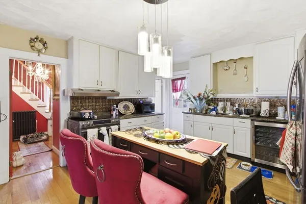 a kitchen with a stove a sink dishwasher and white cabinets with wooden floor