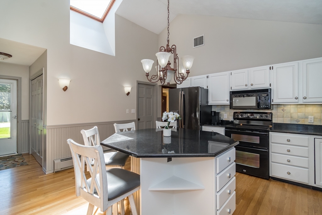 116 Stock Farm Road Sudbury, MA 01776 - Photo 3 of 31 a kitchen with stainless steel appliances granite countertop a stove top oven a refrigerator a dining table and chairs with wooden floor