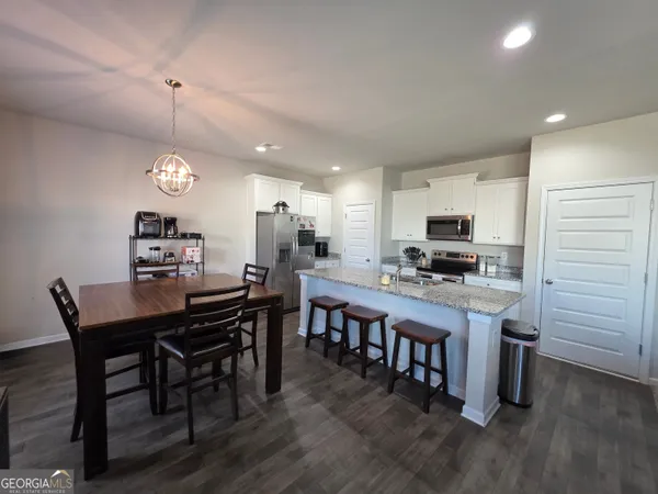 a kitchen with kitchen island granite countertop a dining table chairs and a refrigerator