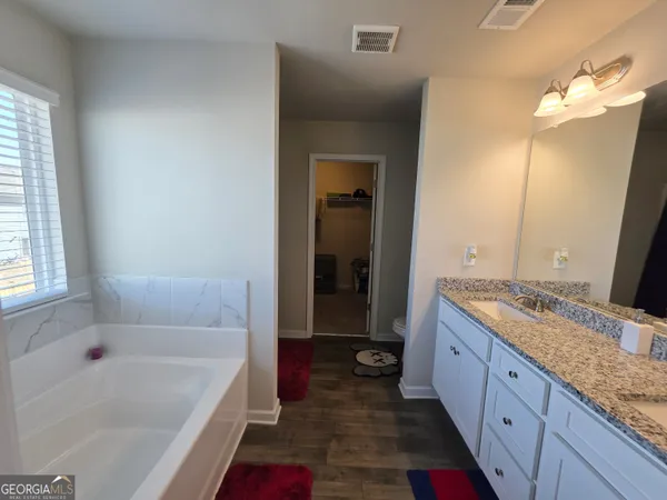 a bathroom with a granite countertop tub sink and mirror