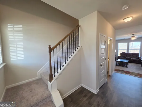 a view of a livingroom with wooden floor and stairs