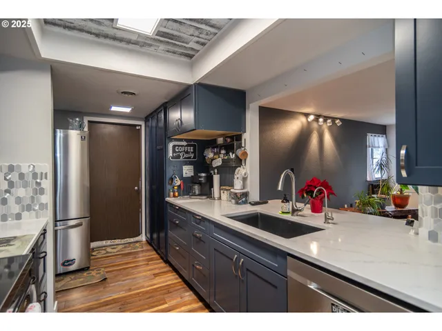 a kitchen with stainless steel appliances kitchen island granite countertop a refrigerator and a sink