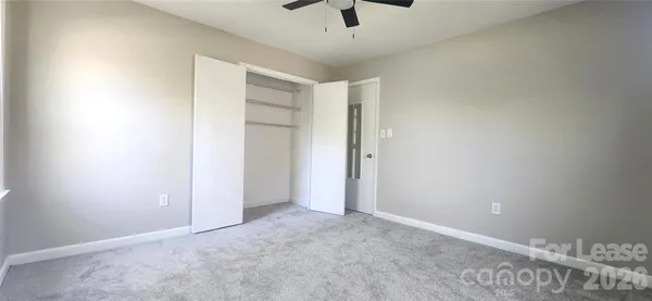an empty room with a ceiling fan and carpet