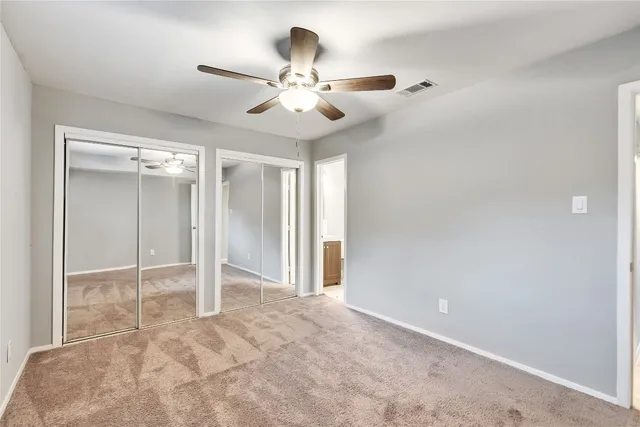 an empty room with closet and a chandelier fan