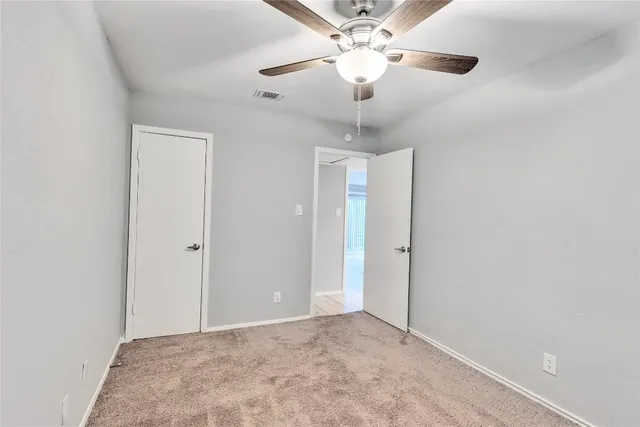 an empty room with a chandelier fan and a ceiling fan