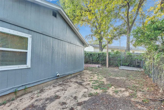 a view of a backyard with large trees and wooden fence