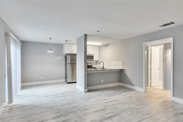 a view of kitchen with refrigerator table and wooden floor