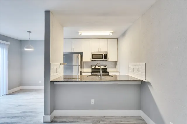 a kitchen with stainless steel appliances granite countertop a sink a stove and a refrigerator