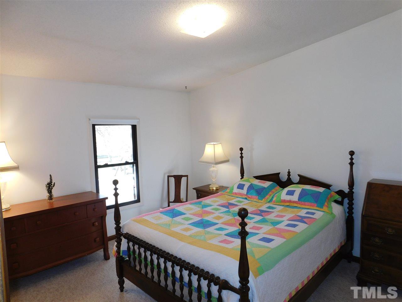 9402 Hampton Road Rougemont, NC 27572 - Photo 11 of 18 a bedroom with a bed and a lamp