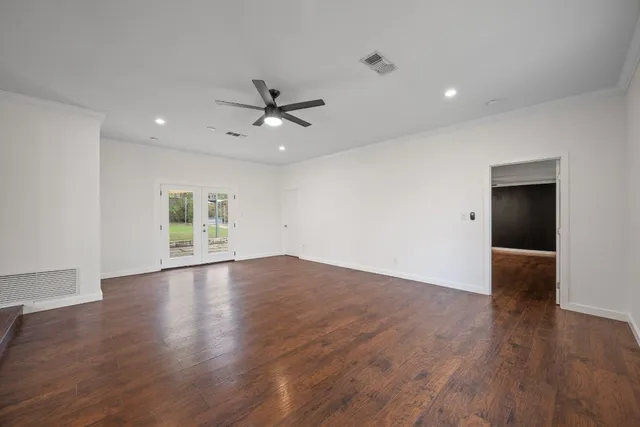 a view of empty room with wooden floor and ceiling fan