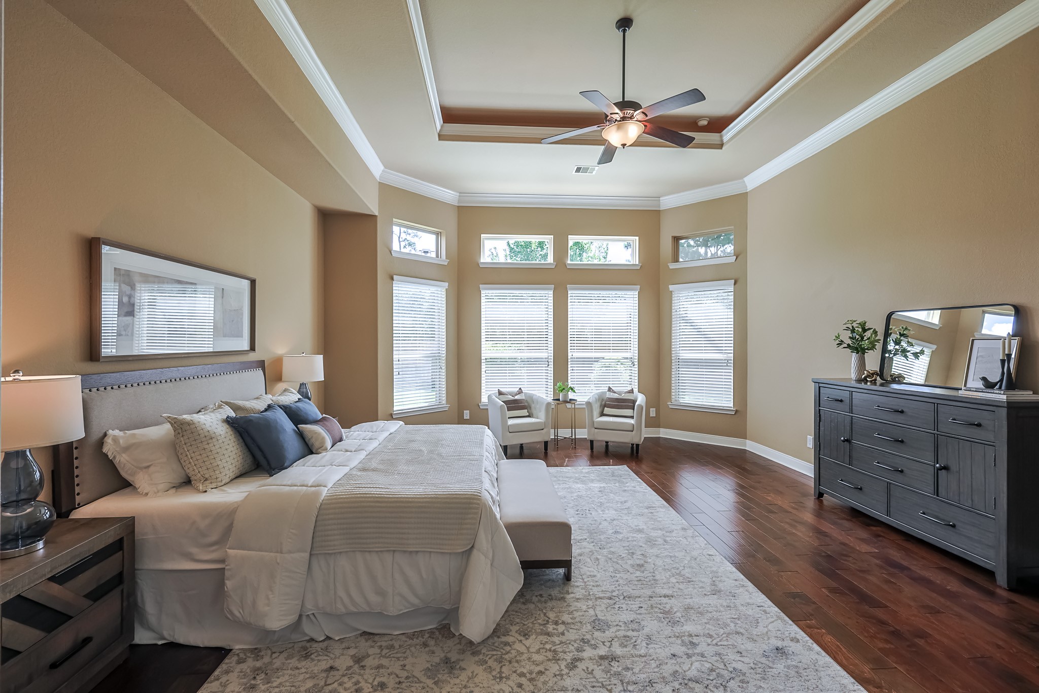 515 Mill Creek Road Pinehurst, TX 77362 - Photo 25 of 48 This spacious bedroom features a tray ceiling with a ceiling fan, large windows for natural light, and elegant hardwood flooring.