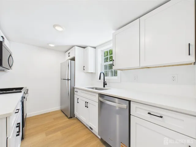 a large white kitchen with stainless steel appliances granite countertop a sink and a stove