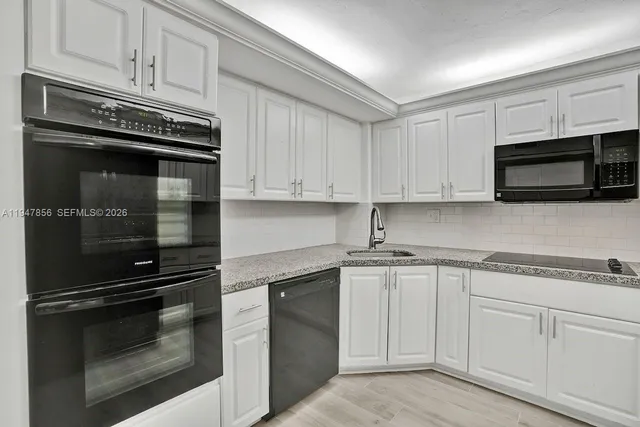 a kitchen with granite countertop white cabinets and stainless steel appliances