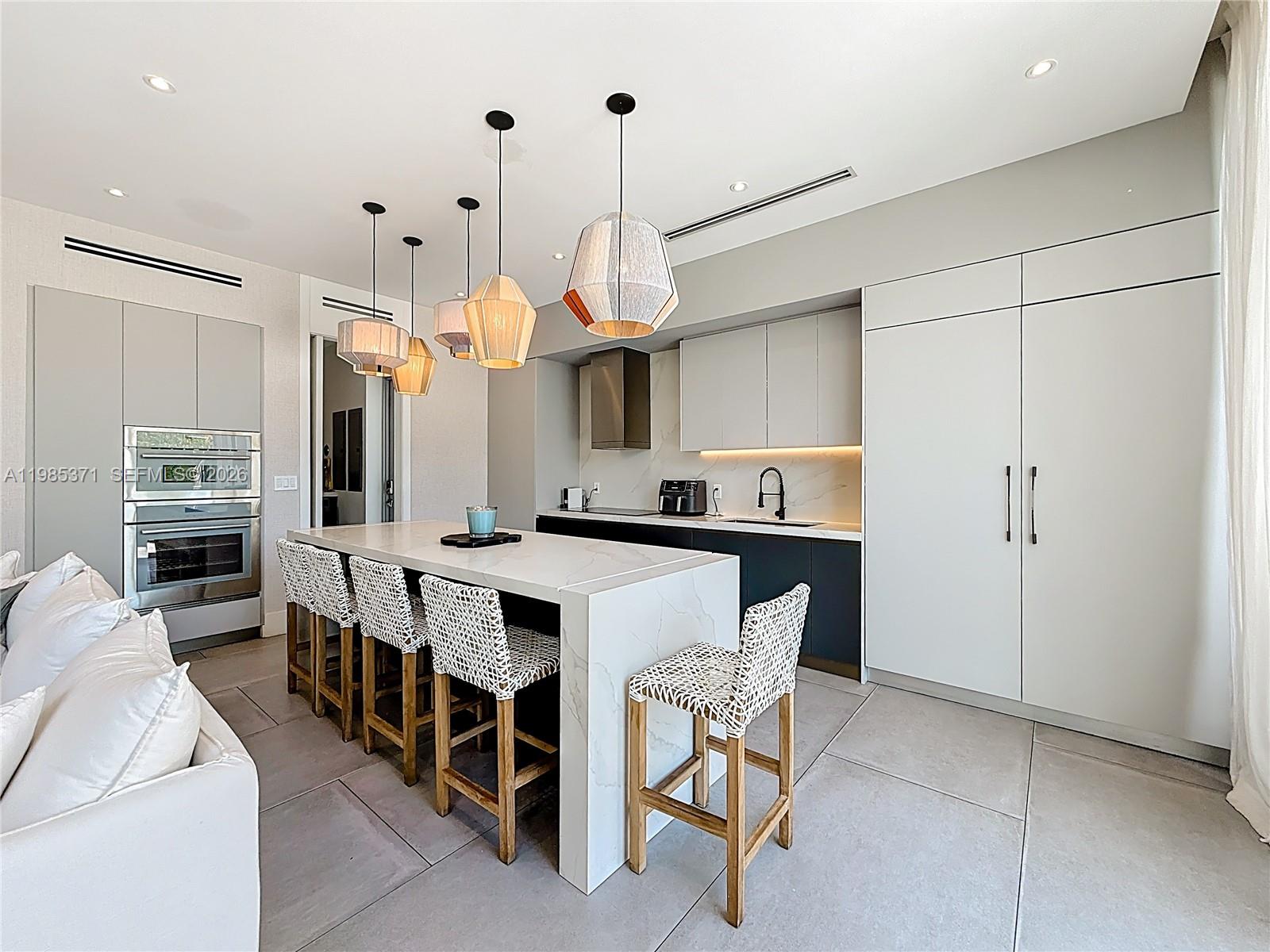 561 Warren Lane Key Biscayne, FL 33149 - Photo 8 of 30 a kitchen with stainless steel appliances kitchen island granite countertop a table chairs and a refrigerator
