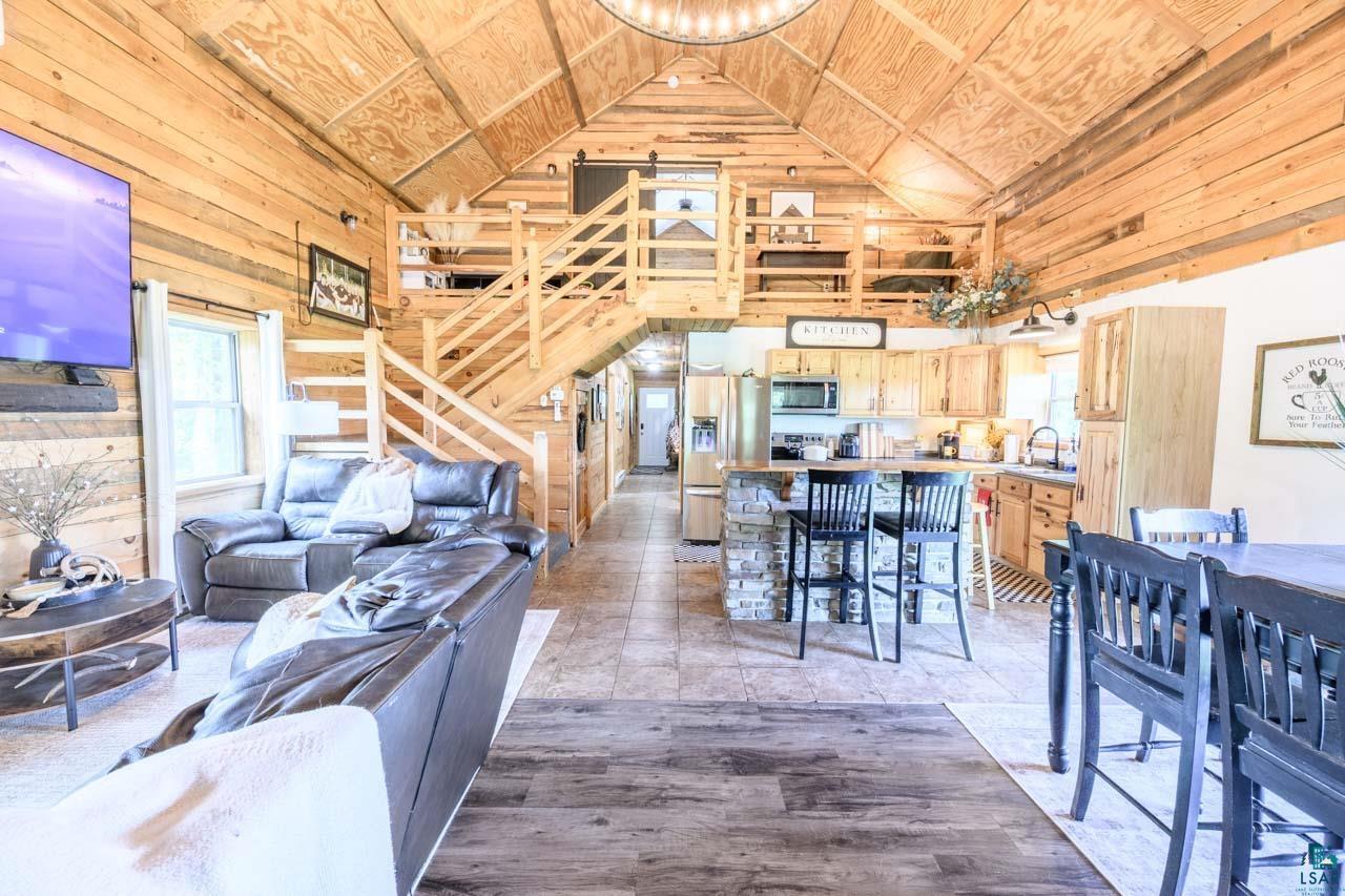 Vaulted wood-paneled ceilings, open-concept design, wood-finish flooring, kitchen island with stone base, and a second-story wood railing