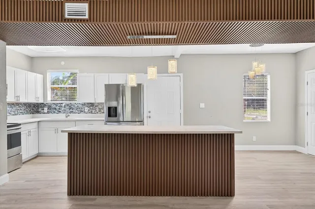 a kitchen with a sink stainless steel appliances wooden floor and cabinets
