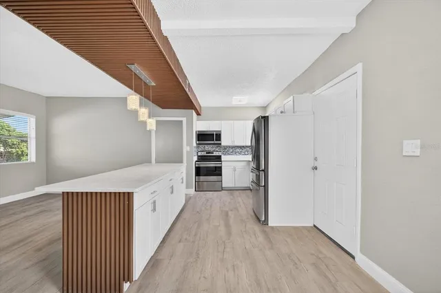 a view of a hallway with kitchen and wooden floor