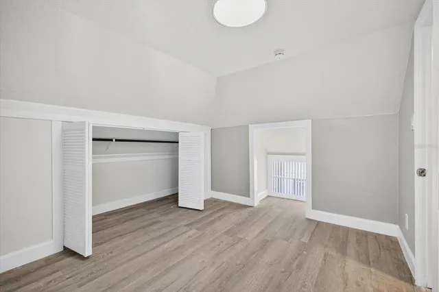 a view of an empty room with wooden floor & closet