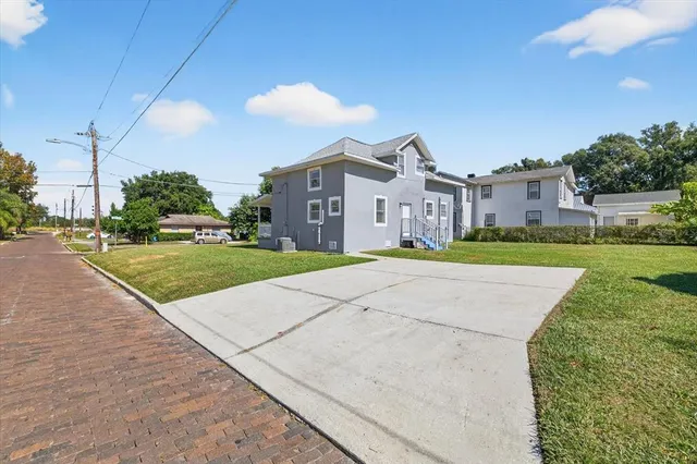 a view of a big house with a big yard and large trees