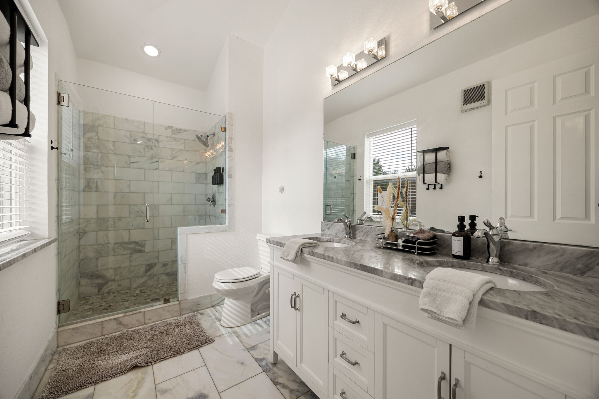 12808 Hughes Street Austin, TX 78732 - Photo 21 of 40 a bathroom with a granite countertop sink a toilet a mirror and shower