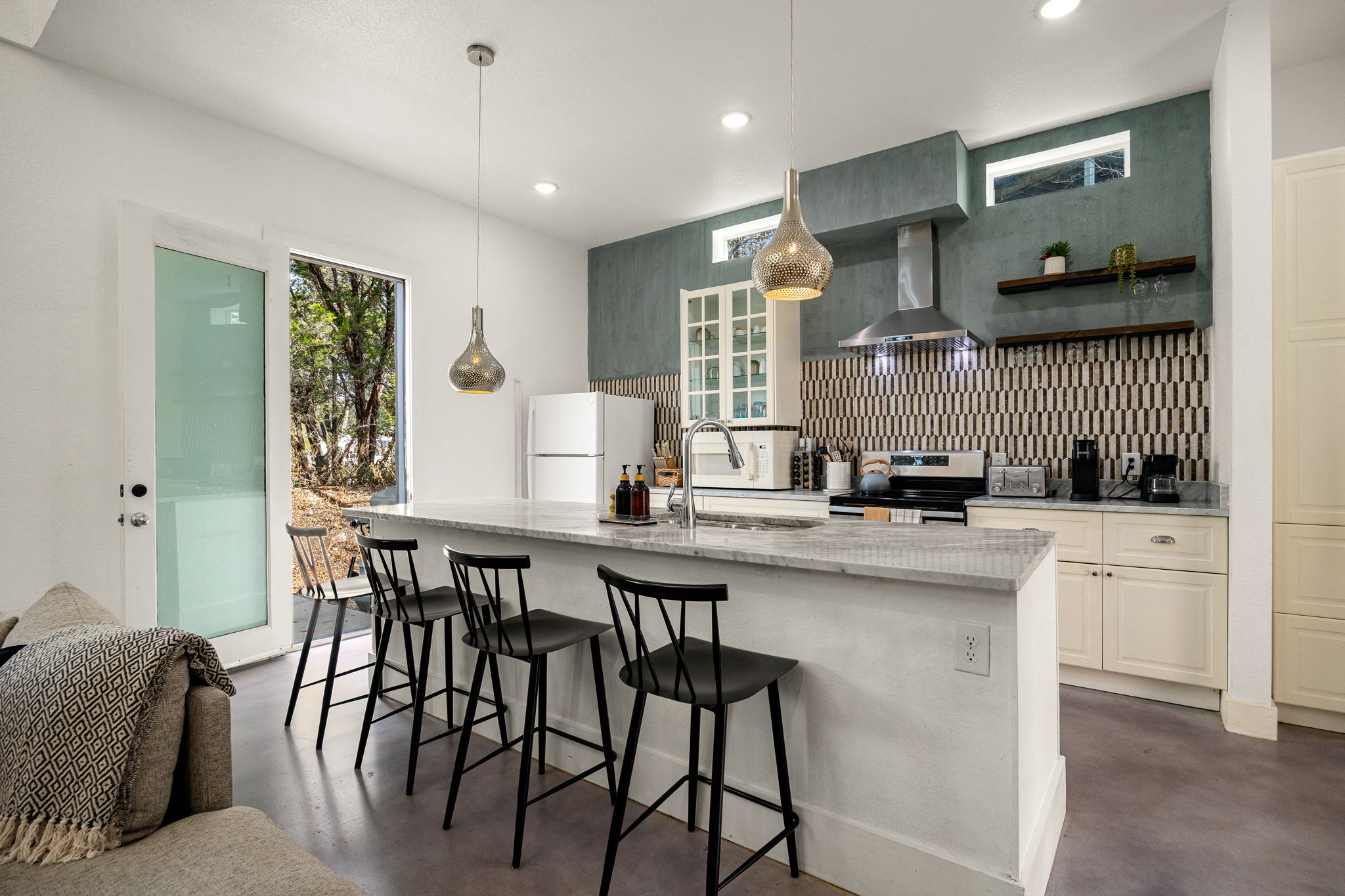 12808 Hughes Street Austin, TX 78732 - Photo 7 of 40 a kitchen with stainless steel appliances kitchen island granite countertop a table chairs sink and cabinets