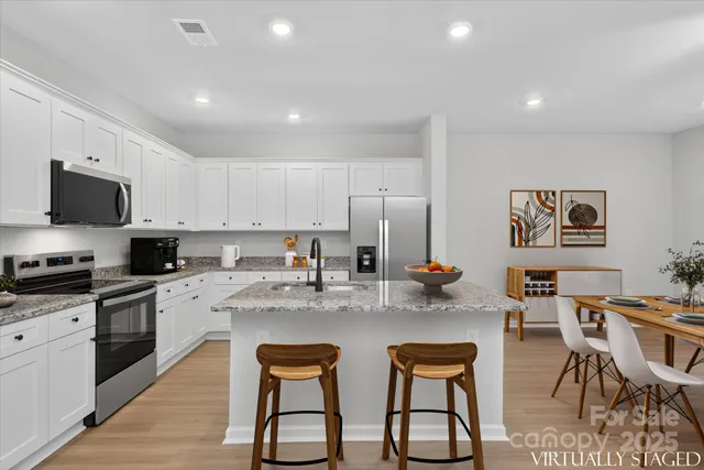 a kitchen with stainless steel appliances granite countertop a stove a sink a dining table and chairs
