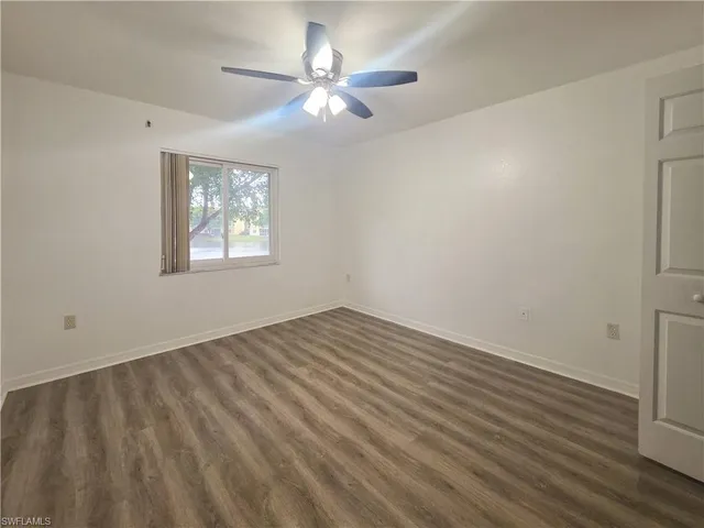 an empty room with wooden floor ceiling fan and windows