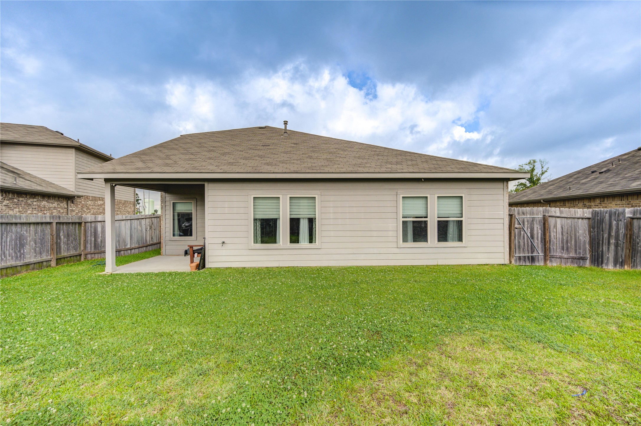 2306 Rainier Mist Road Spring, TX 77373 - Photo 27 of 28 Backyard - Rear view of a single-story home with a neatly maintained lawn and a covered patio. It features a fenced backyard, perfect for privacy and outdoor activities.