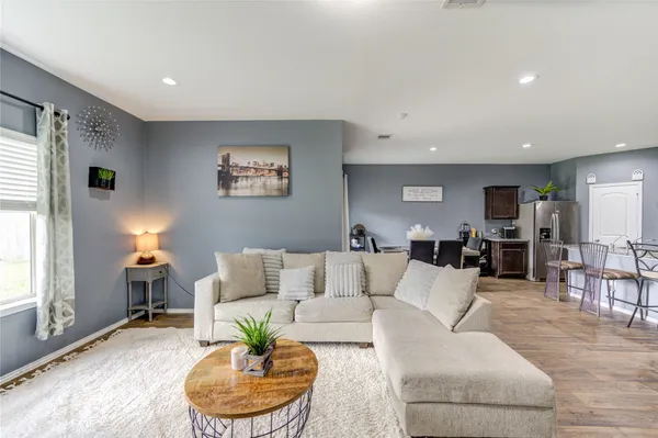 a living room with furniture a wooden floor and a kitchen view