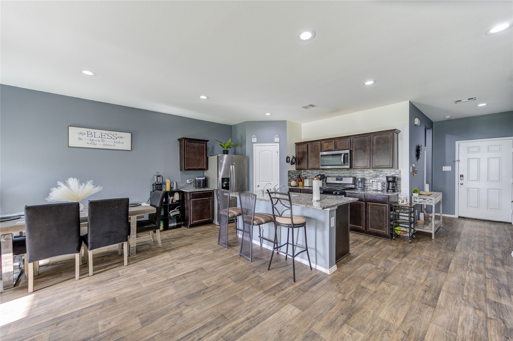 2306 Rainier Mist Road Spring, TX 77373 - Photo 4 of 28 This open-concept kitchen and dining area features modern appliances, dark wood cabinetry, and a stylish island with bar seating.