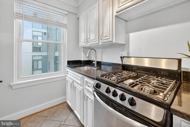 a kitchen with granite countertop a stove and a white cabinets
