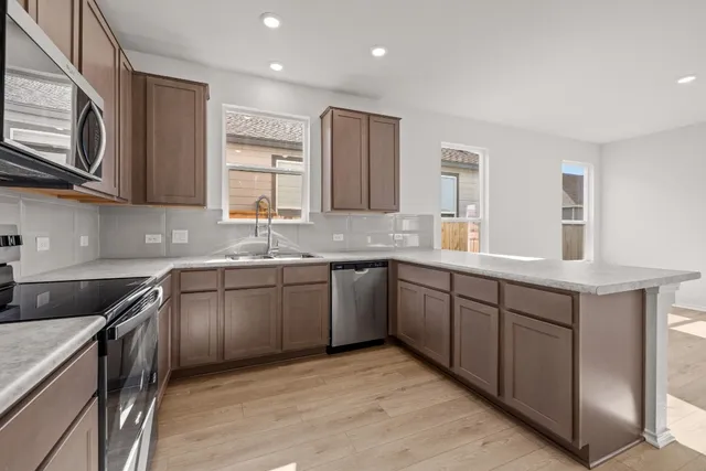 a kitchen with granite countertop cabinets stainless steel appliances a sink and a window