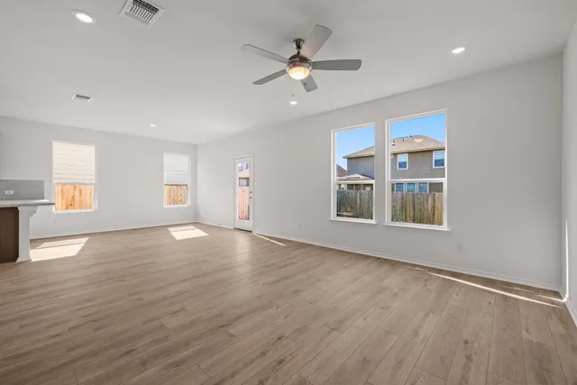a view of an empty room with window and wooden floor